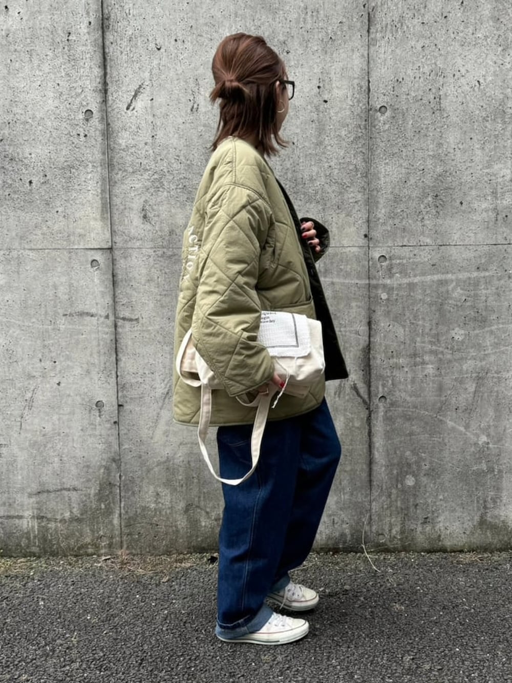 グリーン系のノーカラーコート、ブルー系のサロペット/オーバーオール、ホワイト系のTシャツ/カットソーを着用したレディースの秋コーディネートの4枚目の写真