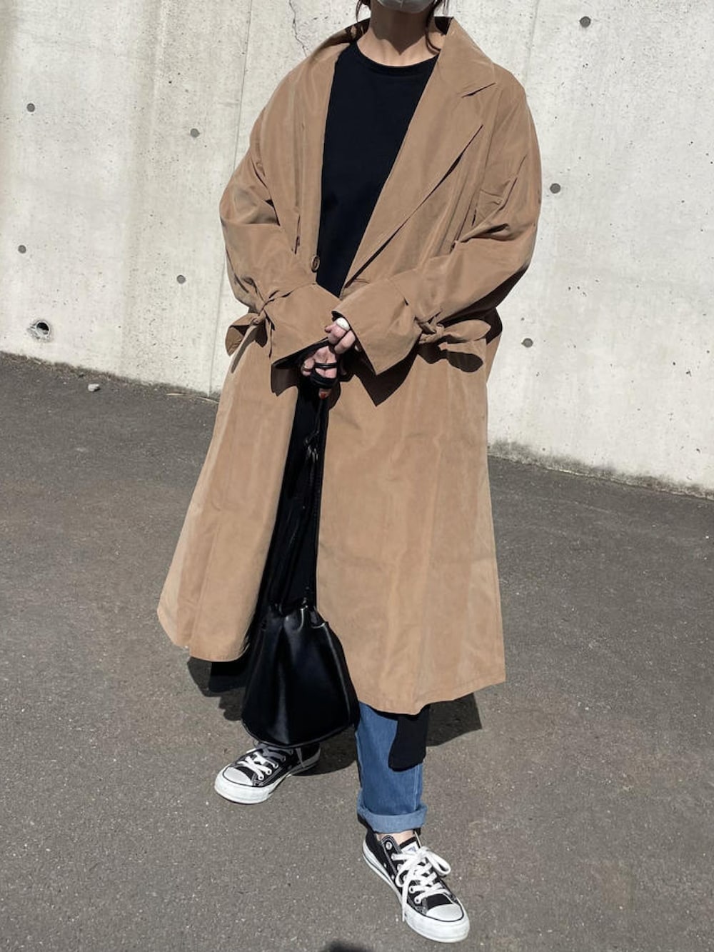 ブラック系のワンピース、ブラウン系のトレンチコート、ブラック系のショルダーバッグを着用したレディースの春コーディネートの3枚目の写真