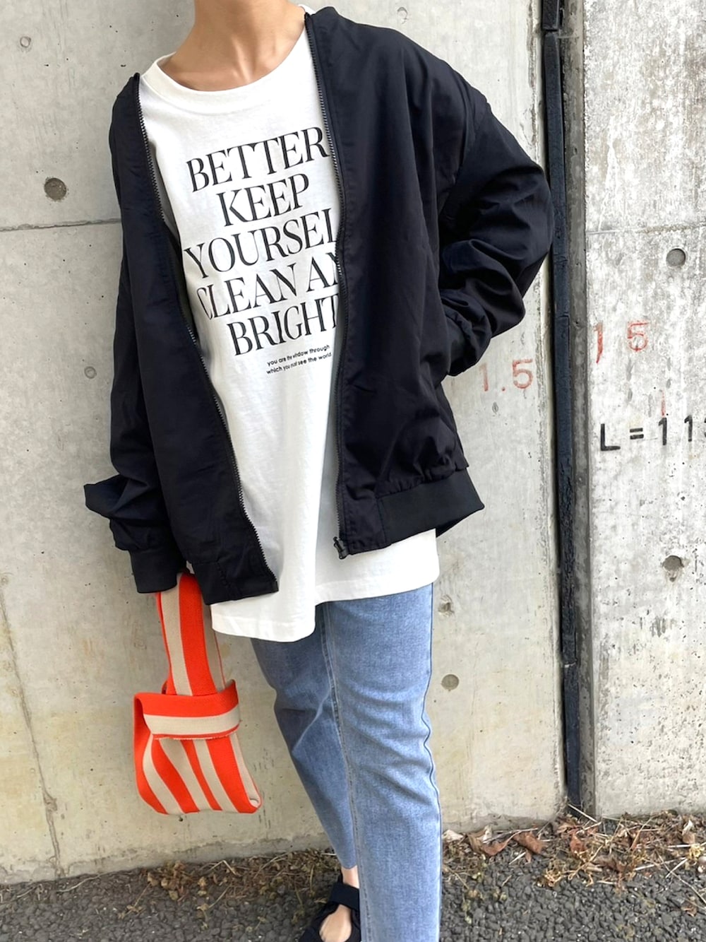 ブラック系のMA-1、ホワイト系のTシャツ/カットソー、オレンジ系のハンドバッグを着用したレディースの春コーディネートの3枚目の写真