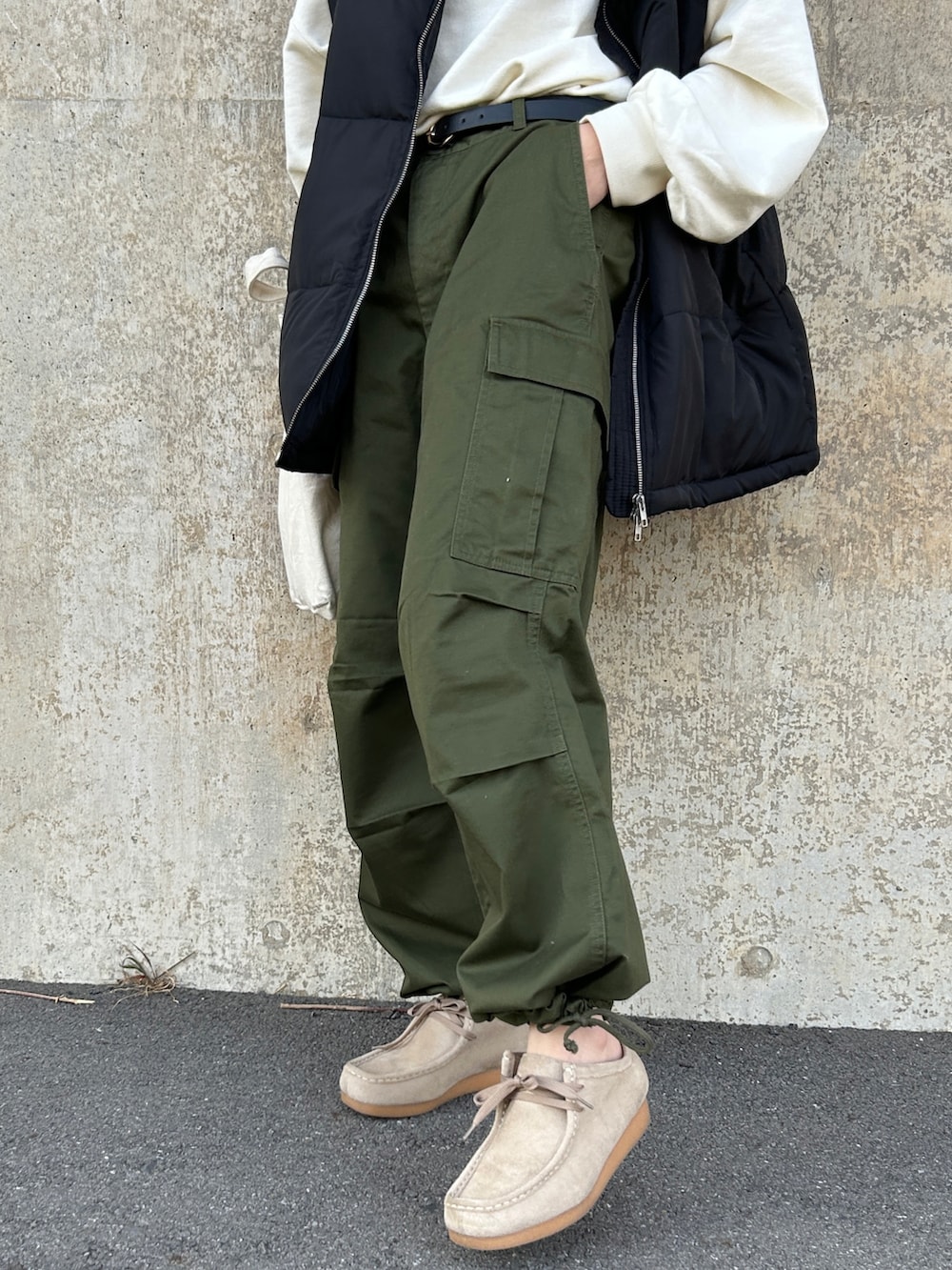 ホワイト系のスウェット、ブラック系のダウンベスト、グリーン系のカーゴパンツを着用したレディースの冬コーディネートの3枚目の写真