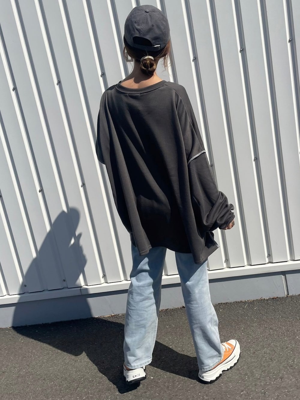 グレー系のスウェット、ブルー系のデニムパンツ、ホワイト系のバックパック/リュックを着用したレディースの春コーディネートの3枚目の写真