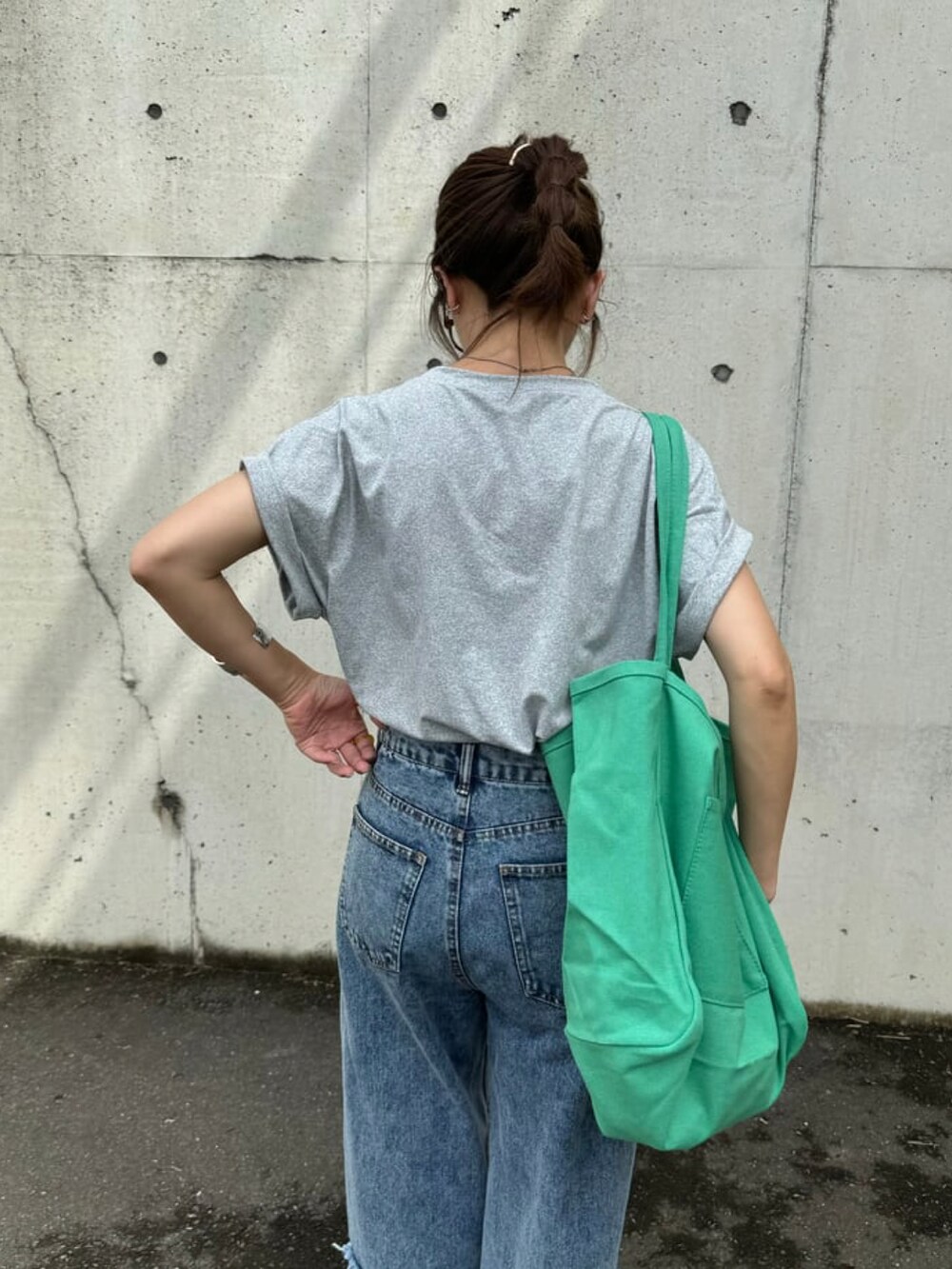 グレー系のTシャツ/カットソー、ブルー系のデニムパンツ、ピンク系のトートバッグを着用したレディースの夏コーディネートの4枚目の写真