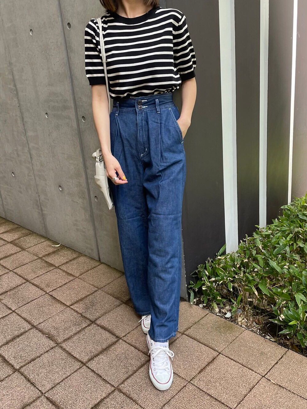 ブラック系のTシャツ/カットソー、ブルー系のデニムパンツ、ホワイト系のスニーカーを着用したレディースの春コーディネートの2枚目の写真