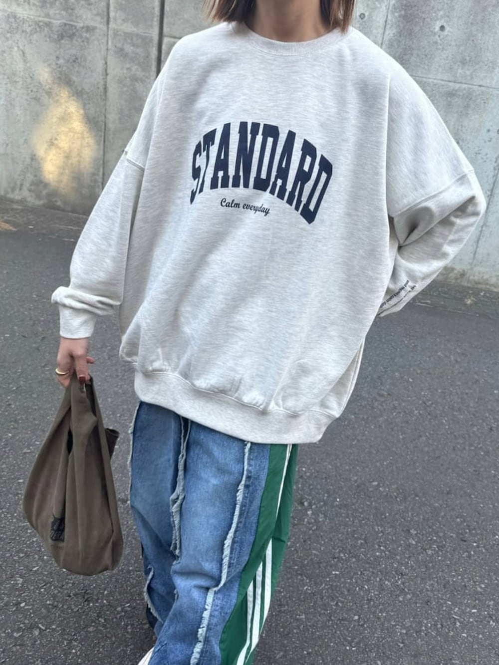 グレー系のスウェット、ブルー系のデニムパンツ、ホワイト系のスニーカーを着用したレディースの冬コーディネートの4枚目の写真