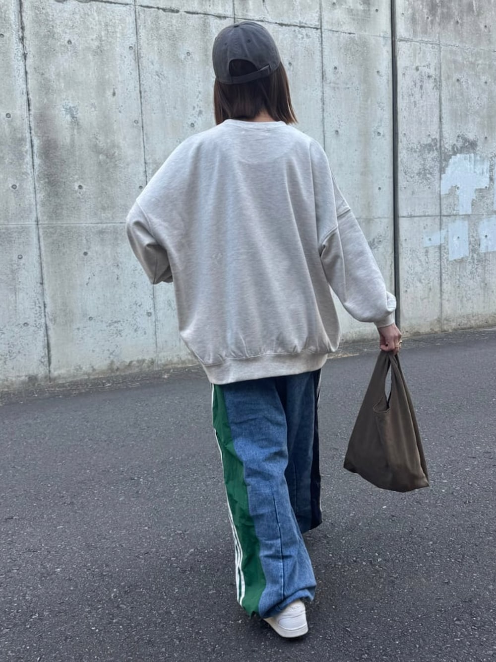 グレー系のスウェット、ブルー系のデニムパンツ、ホワイト系のスニーカーを着用したレディースの冬コーディネートの5枚目の写真