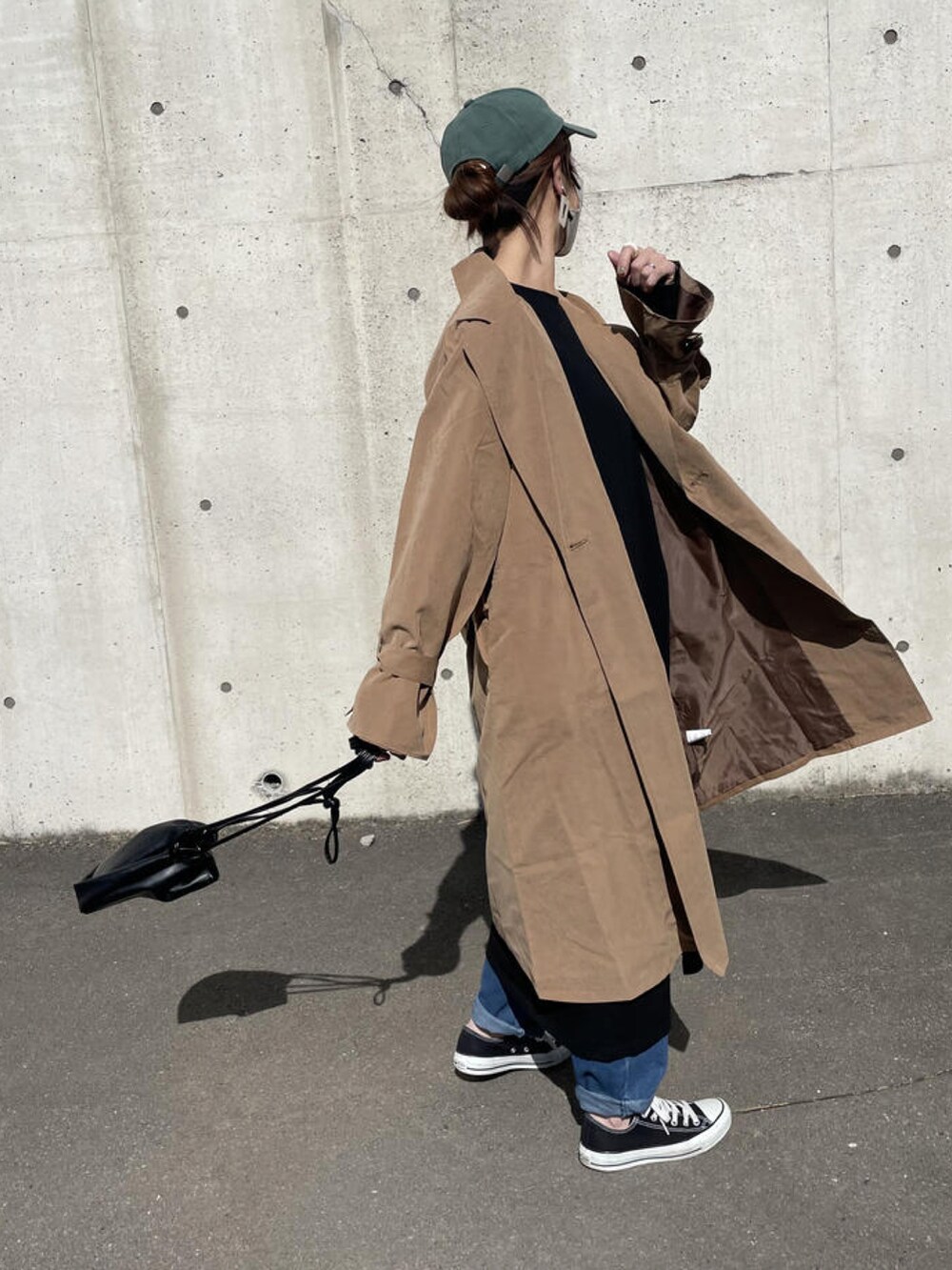 ブラック系のワンピース、ブラウン系のトレンチコート、ブラック系のショルダーバッグを着用したレディースの春コーディネートの5枚目の写真