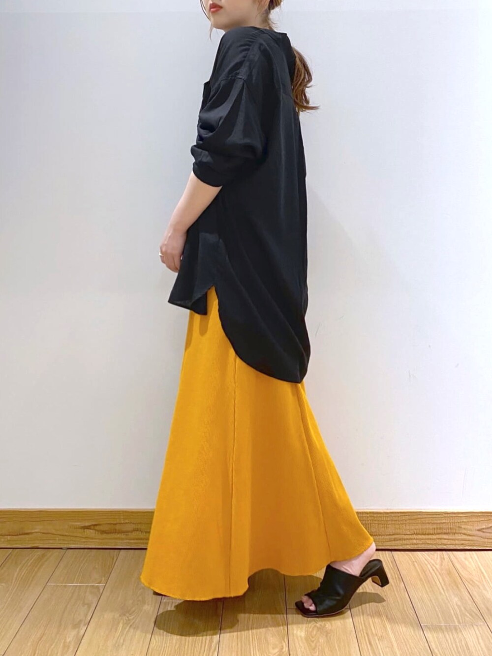 ブラック系のショルダーバッグ、ブラック系のシャツ/ブラウス、オレンジ系のスカートを着用したレディースの春コーディネートの2枚目の写真