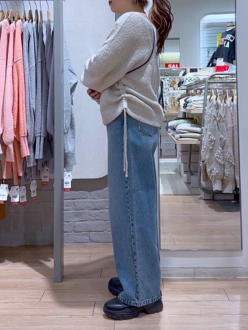 ブラック系のショルダーバッグ、ブラック系のブーツ、ブルー系のデニムパンツを着用したレディースの冬コーディネートの3枚目の写真