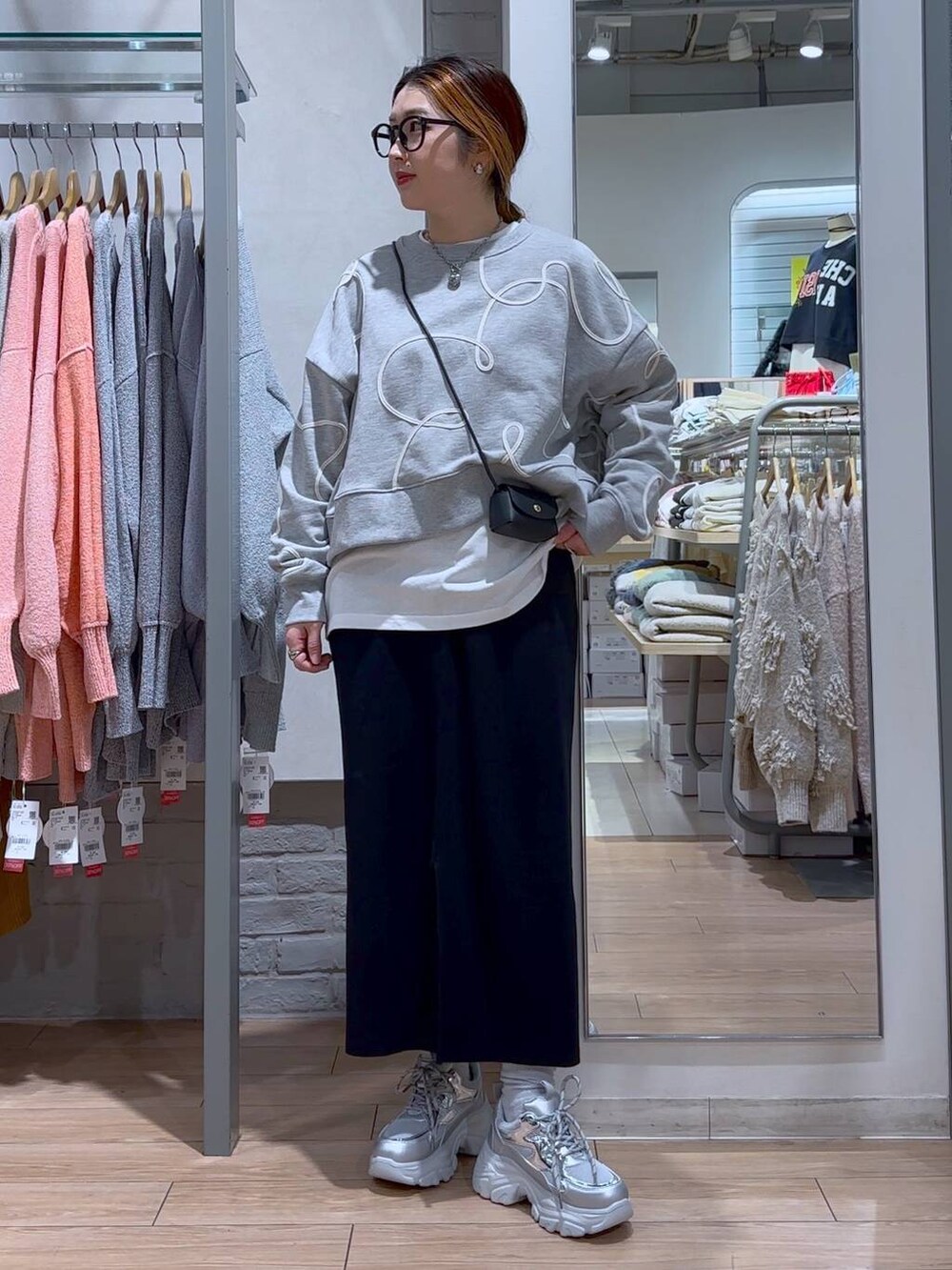 ブラック系のスカート、ブラック系のショルダーバッグ、シルバー系のスニーカーを着用したレディースの冬コーディネートの2枚目の写真