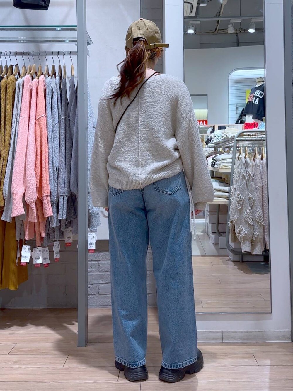 ブラック系のショルダーバッグ、ブラック系のブーツ、ブルー系のデニムパンツを着用したレディースの冬コーディネートの4枚目の写真