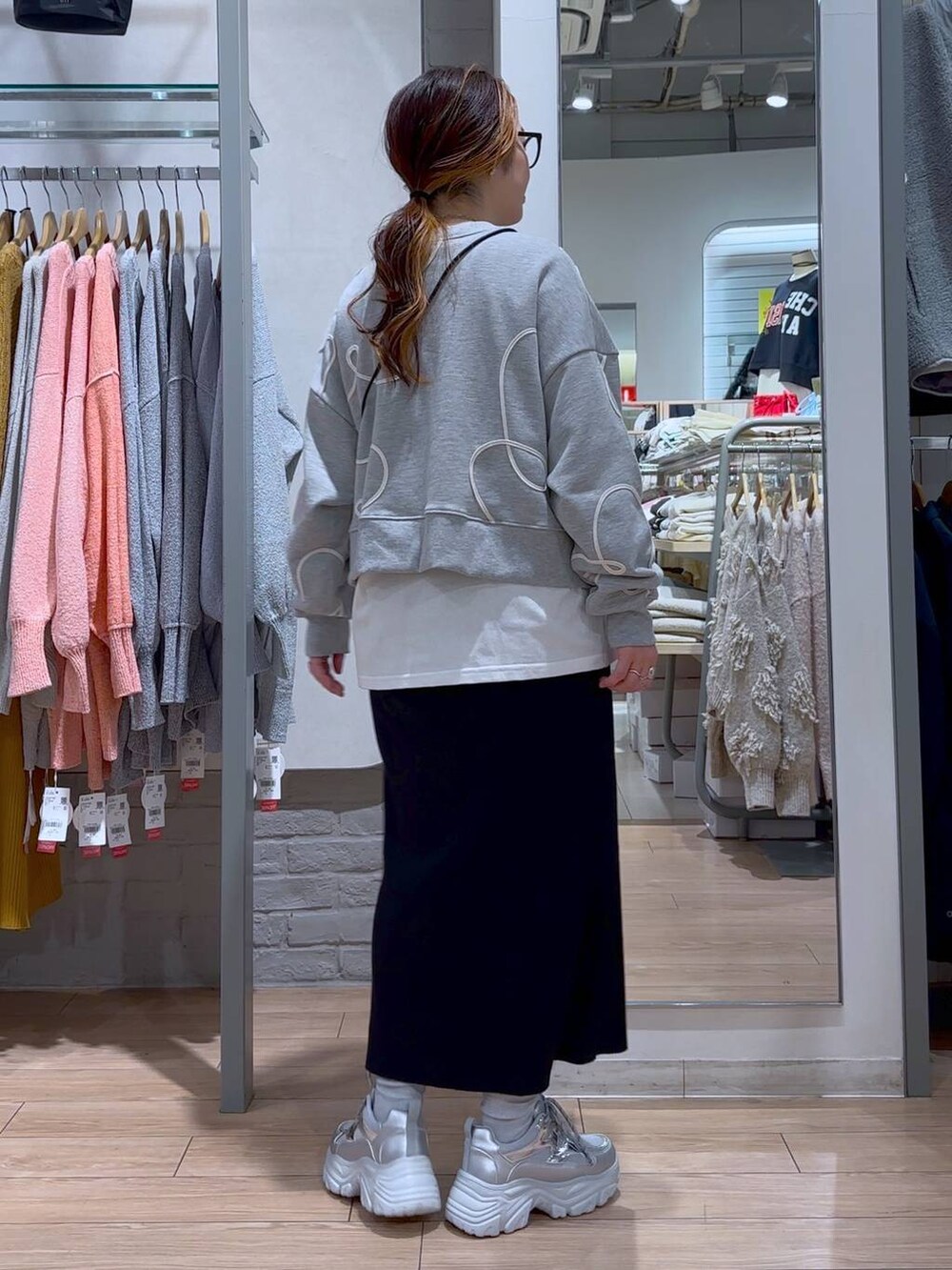 ブラック系のスカート、ブラック系のショルダーバッグ、シルバー系のスニーカーを着用したレディースの冬コーディネートの5枚目の写真