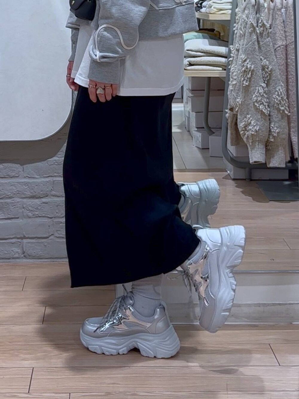 ブラック系のスカート、ブラック系のショルダーバッグ、シルバー系のスニーカーを着用したレディースの冬コーディネートの8枚目の写真