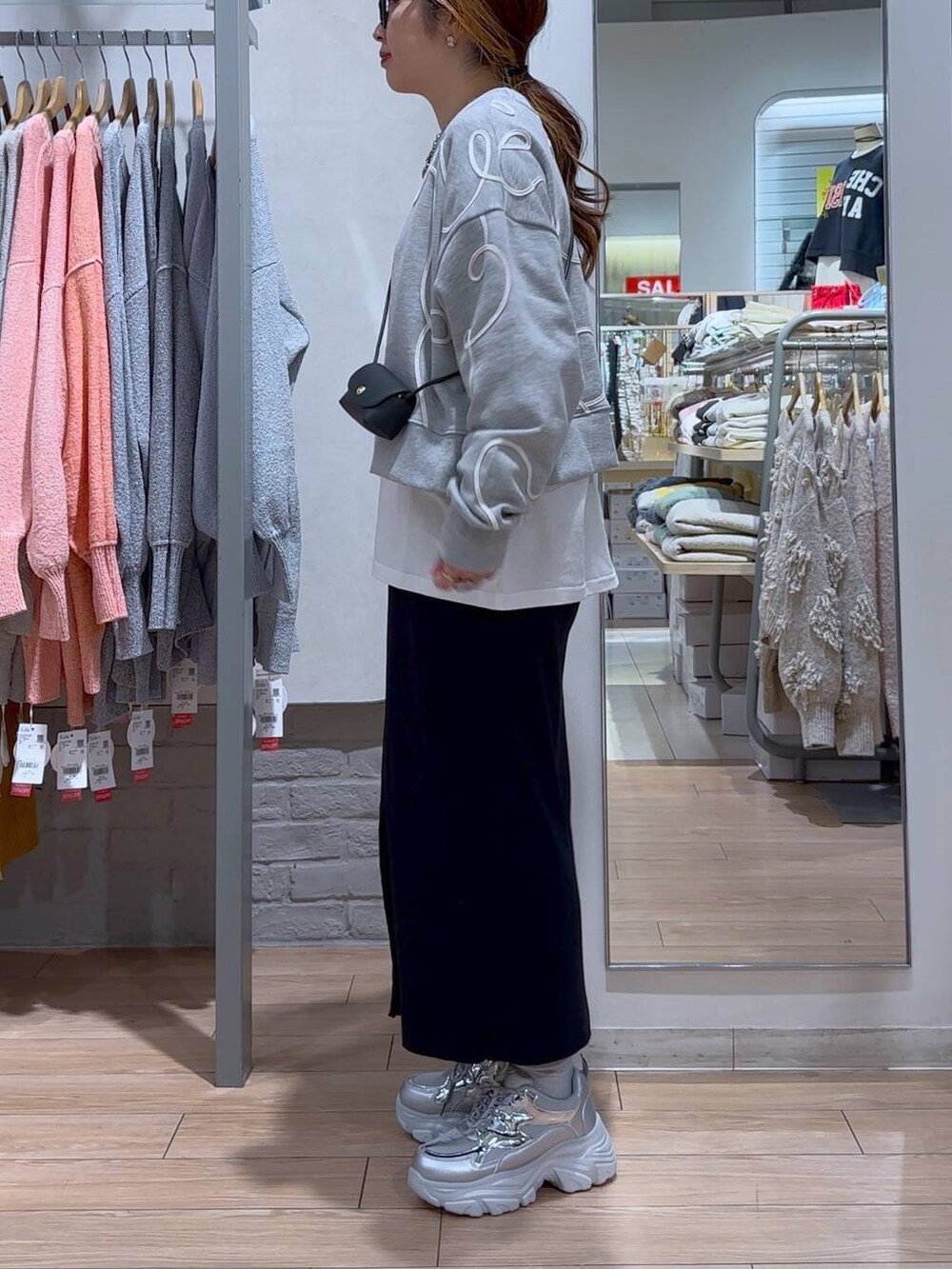 ブラック系のスカート、ブラック系のショルダーバッグ、シルバー系のスニーカーを着用したレディースの冬コーディネートの4枚目の写真