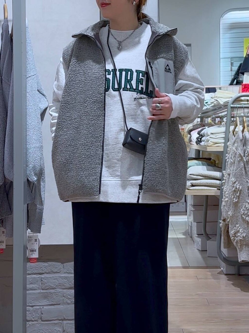 ブラック系のスカート、ブラック系のショルダーバッグ、シルバー系のスニーカーを着用したレディースの冬コーディネートの4枚目の写真