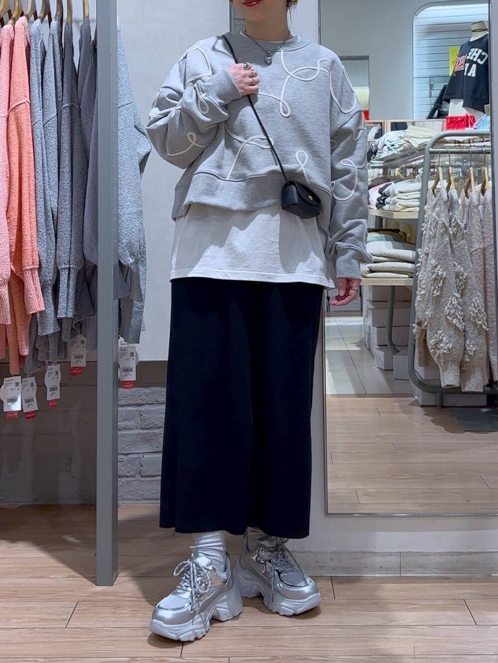 ブラック系のスカート、ブラック系のショルダーバッグ、シルバー系のスニーカーを着用したレディースの冬コーディネートの3枚目の写真