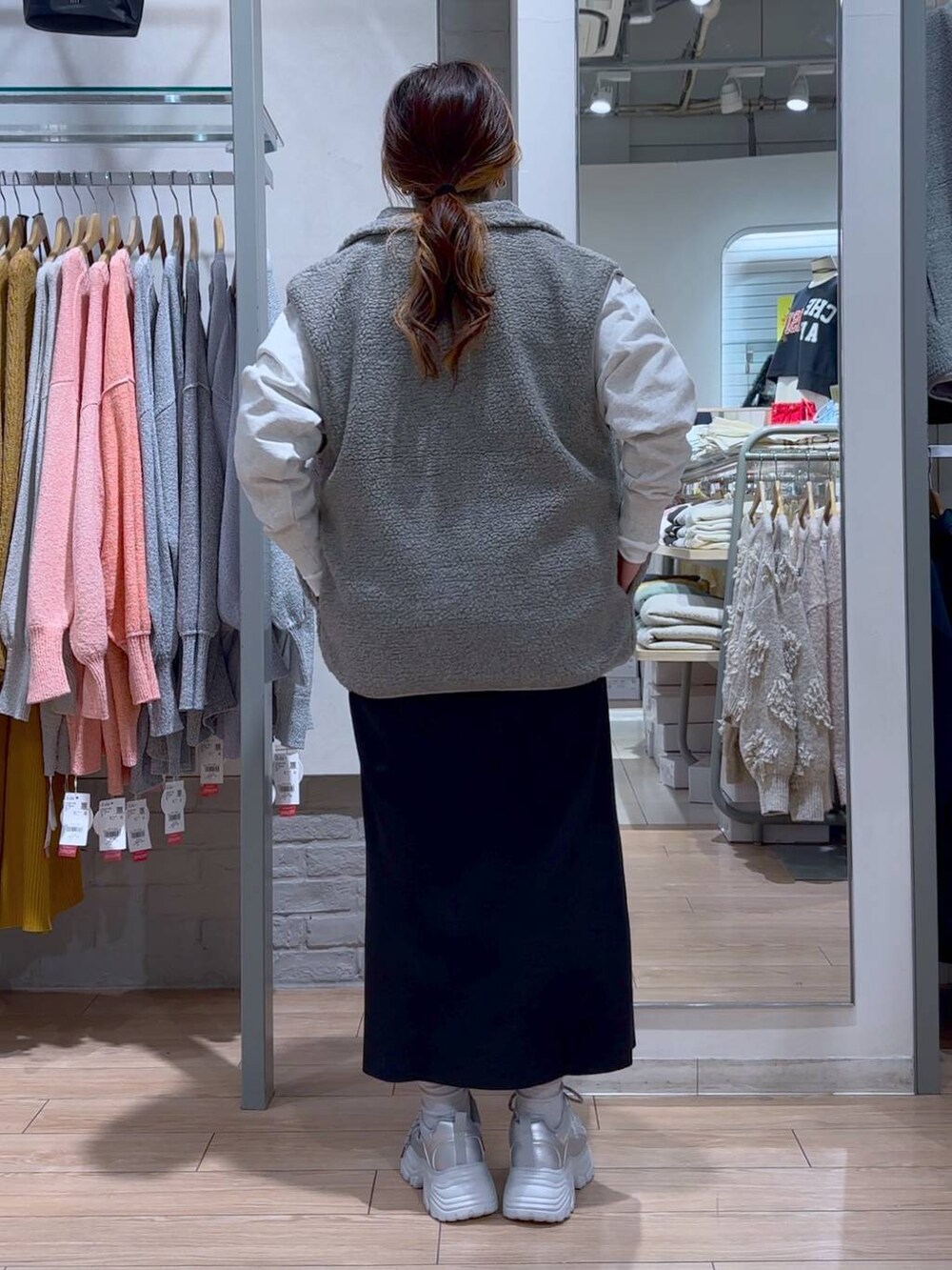 ブラック系のスカート、ブラック系のショルダーバッグ、シルバー系のスニーカーを着用したレディースの冬コーディネートの6枚目の写真