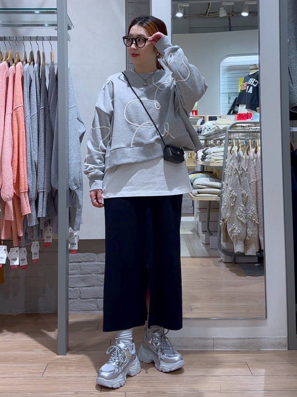 ブラック系のスカート、ブラック系のショルダーバッグ、シルバー系のスニーカーを着用したレディースの冬コーディネートの6枚目の写真