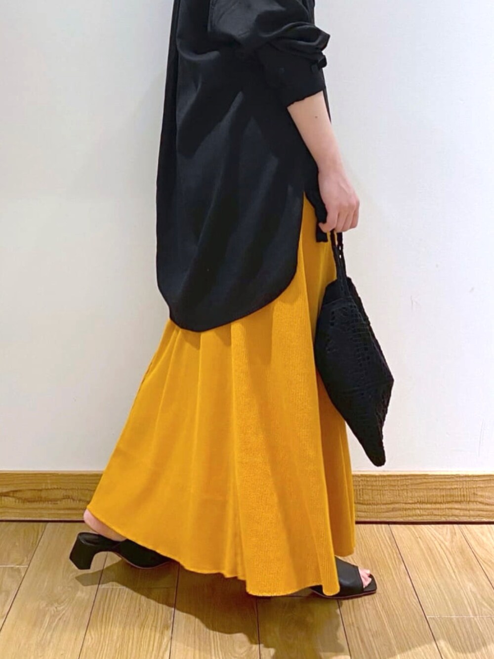 ブラック系のショルダーバッグ、ブラック系のシャツ/ブラウス、オレンジ系のスカートを着用したレディースの春コーディネートの3枚目の写真