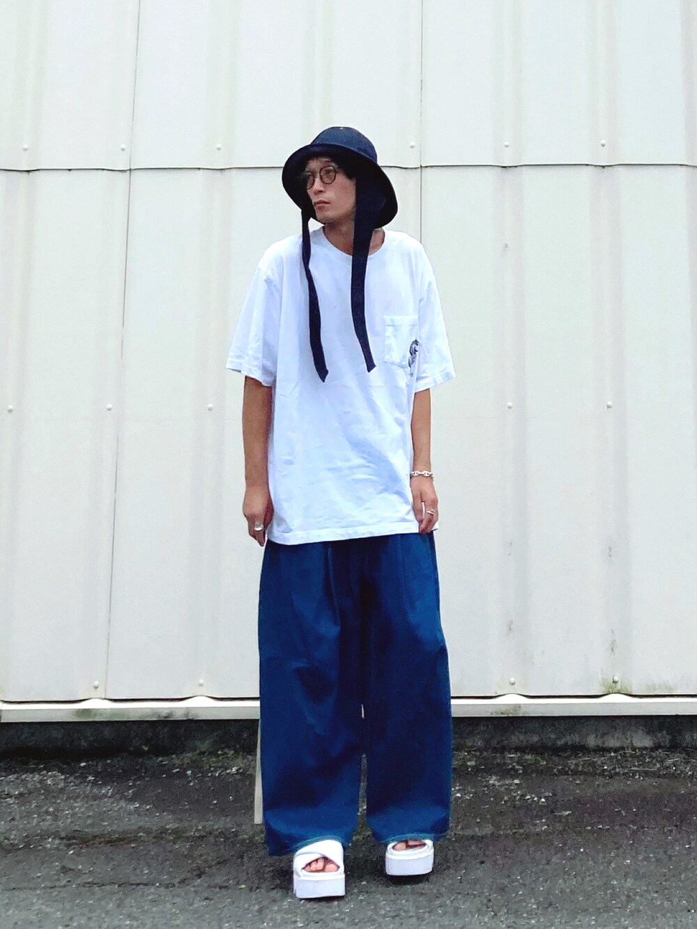 ブルー系のデニムパンツ、ホワイト系のサンダル、ホワイト系のTシャツ/カットソーを着用したメンズの夏コーディネートの2枚目の写真