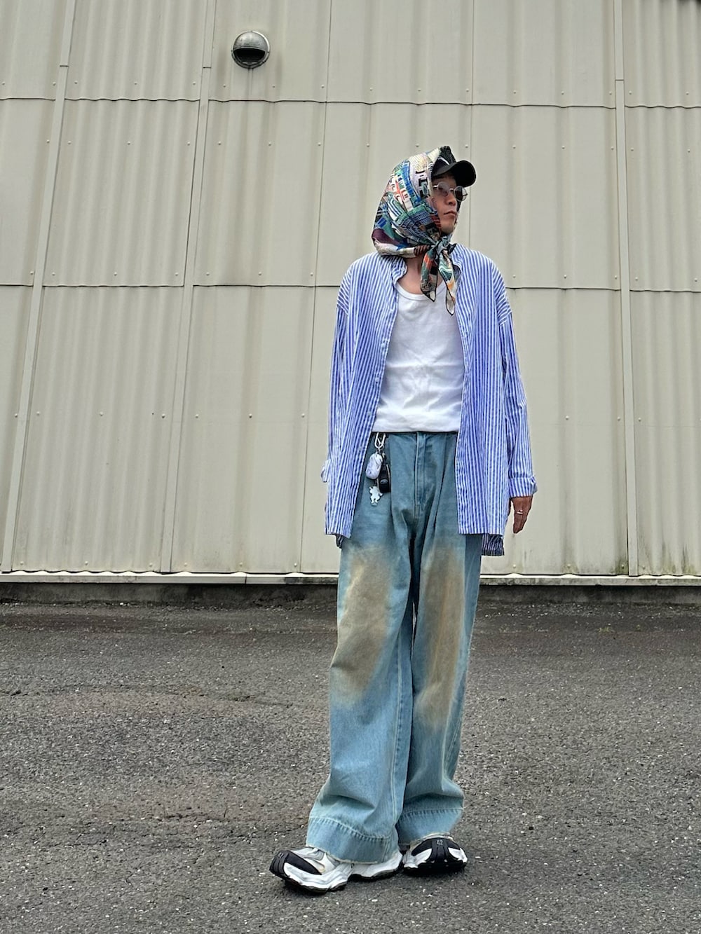 ブルー系のデニムパンツ、ホワイト系のタンクトップ、ホワイト系のスニーカーを着用したメンズの夏コーディネートの2枚目の写真