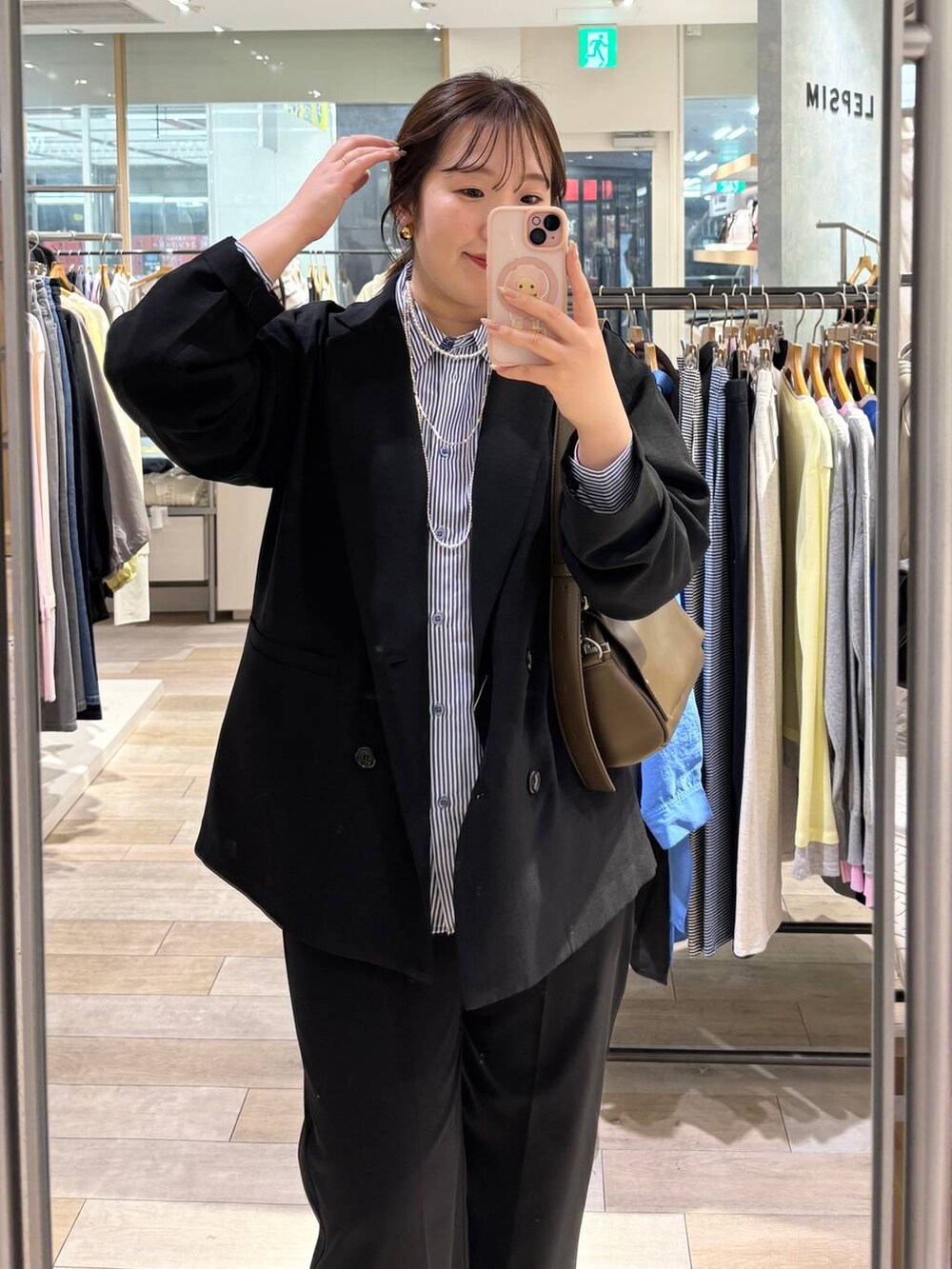 ブラウン系のショルダーバッグ、ホワイト系のパンプス、ブルー系のシャツ/ブラウスを着用したレディースの春コーディネートの2枚目の写真