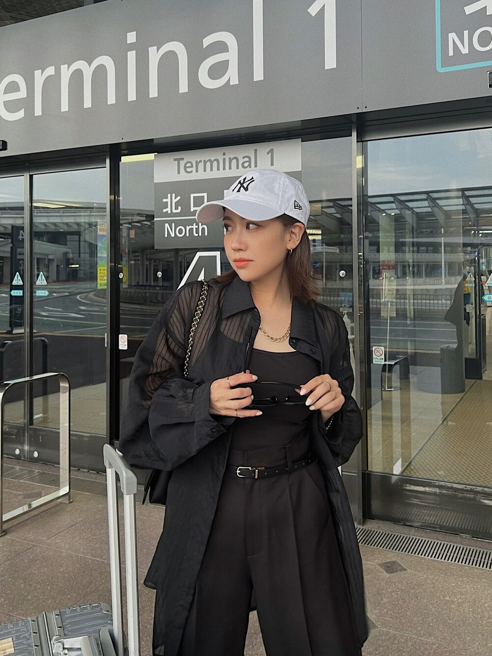 ブラック系のショルダーバッグ、ブラック系のシャツ/ブラウス、ブラック系のスラックスを着用したレディースの夏コーディネートの3枚目の写真