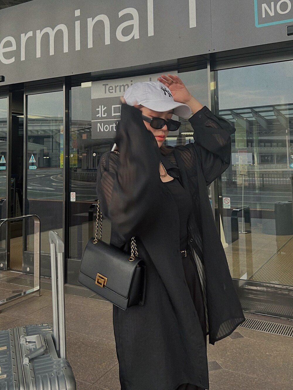 ブラック系のショルダーバッグ、ブラック系のシャツ/ブラウス、ブラック系のスラックスを着用したレディースの夏コーディネートの2枚目の写真