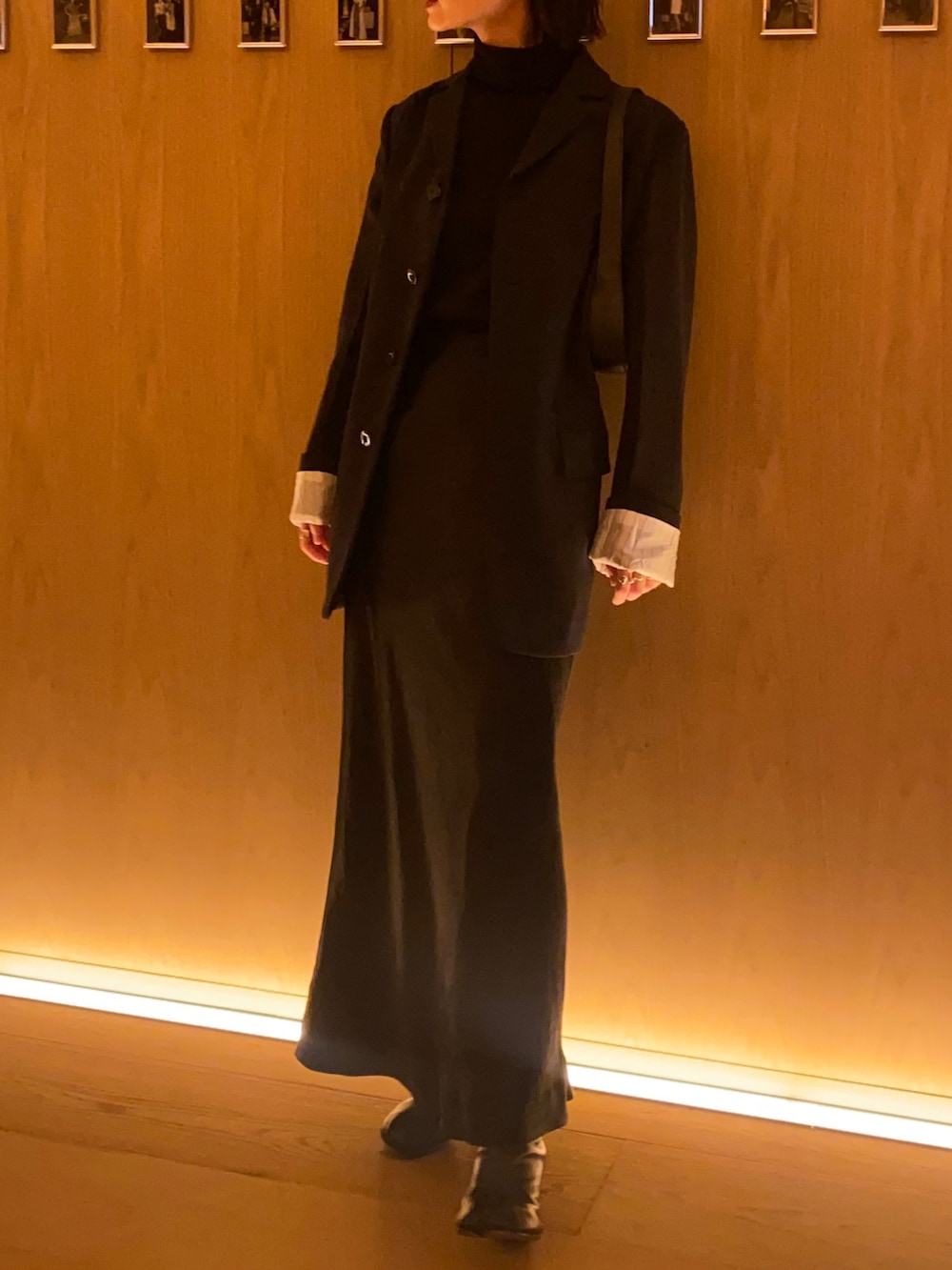 ブラック系のスカート、ブラック系のテーラードジャケット、ブラック系のブーツを着用したレディースの秋コーディネートの2枚目の写真