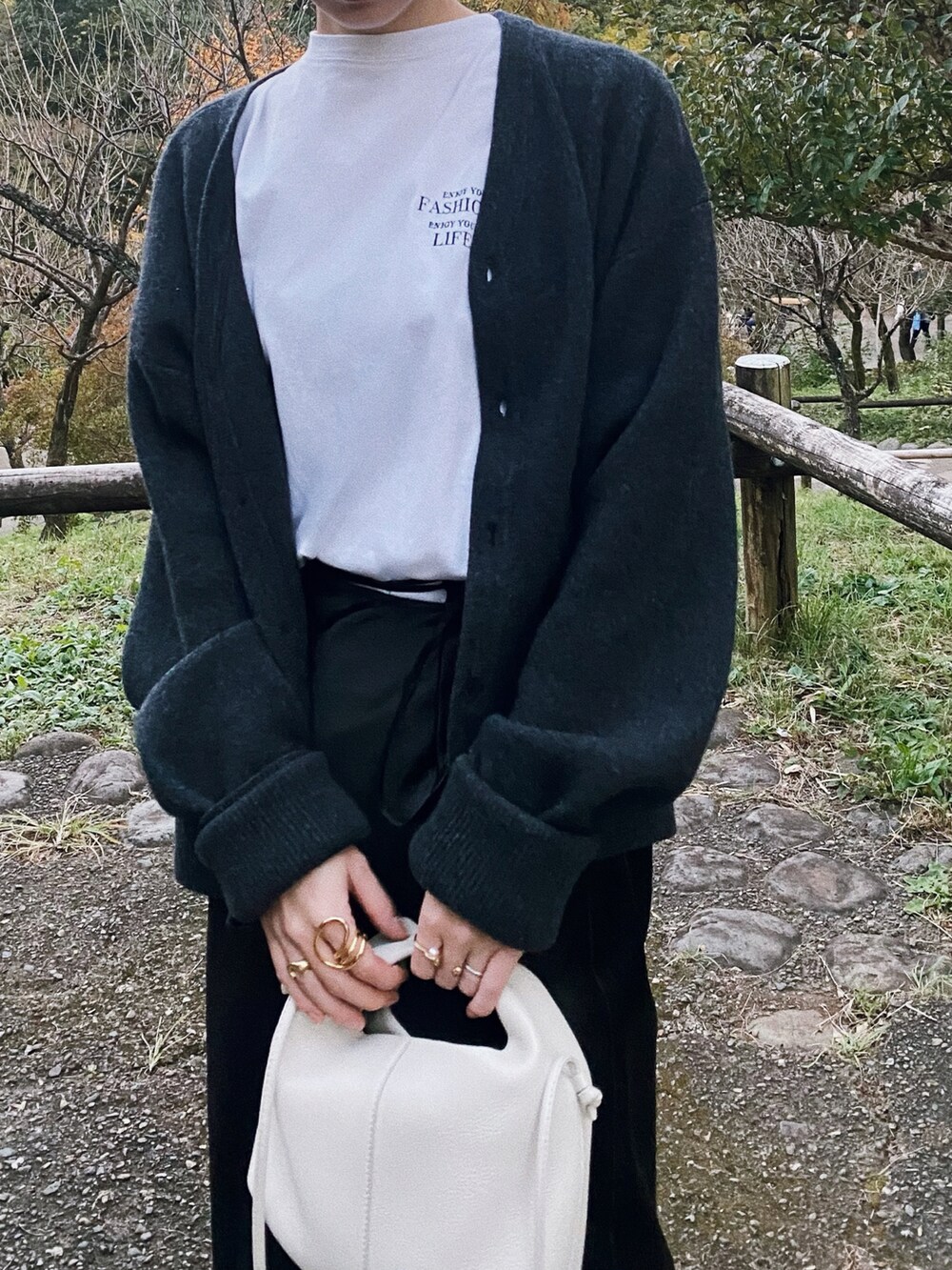 ブラック系のスカート、グレー系のカーディガン/ボレロ、ホワイト系のTシャツ/カットソーを着用したレディースの秋コーディネートの2枚目の写真