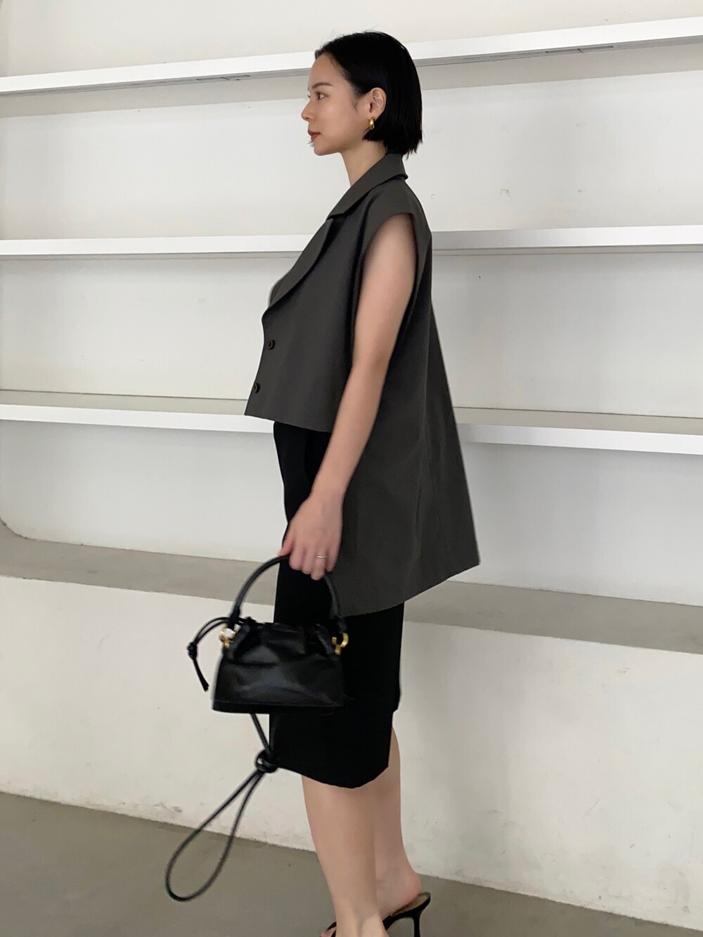 グレー系のベスト、ブラック系のハンドバッグを着用したレディースの春コーディネートの2枚目の写真