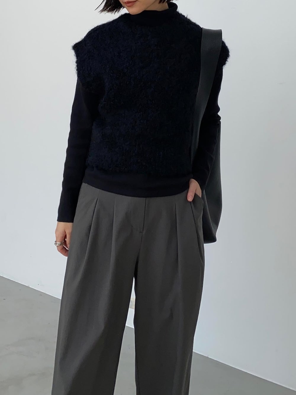 グレー系のスラックス、ブラック系のトートバッグ、ブラック系のブーツを着用したレディースの秋コーディネートの4枚目の写真