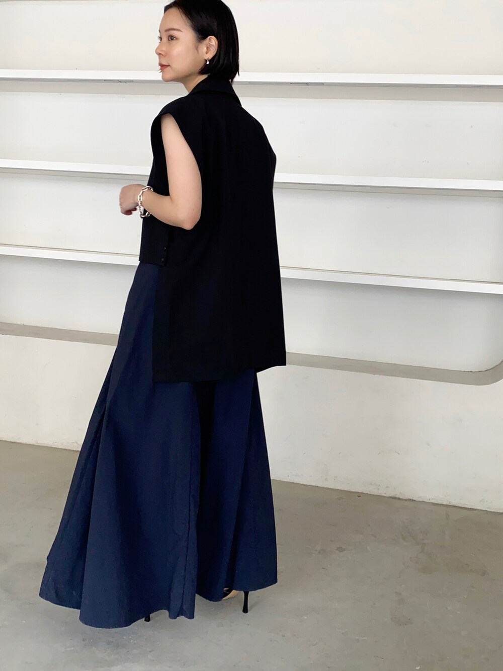 ブルー系のスカート、ブラック系のベストを着用したレディースの春コーディネートの2枚目の写真