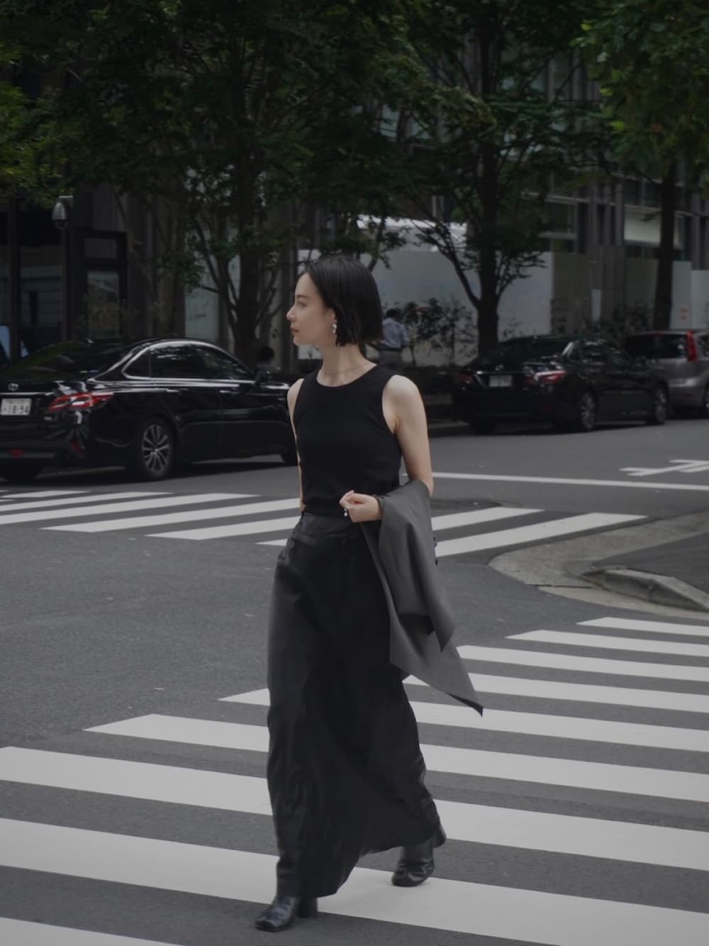 ブラック系のスカート、ブラック系のブーツ、ブラック系のハンドバッグを着用したレディースの夏コーディネートの2枚目の写真