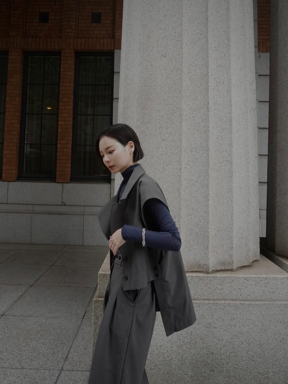 ブルー系のトップス、グレー系のスラックス、グレー系のベストを着用したレディースの夏コーディネートの3枚目の写真