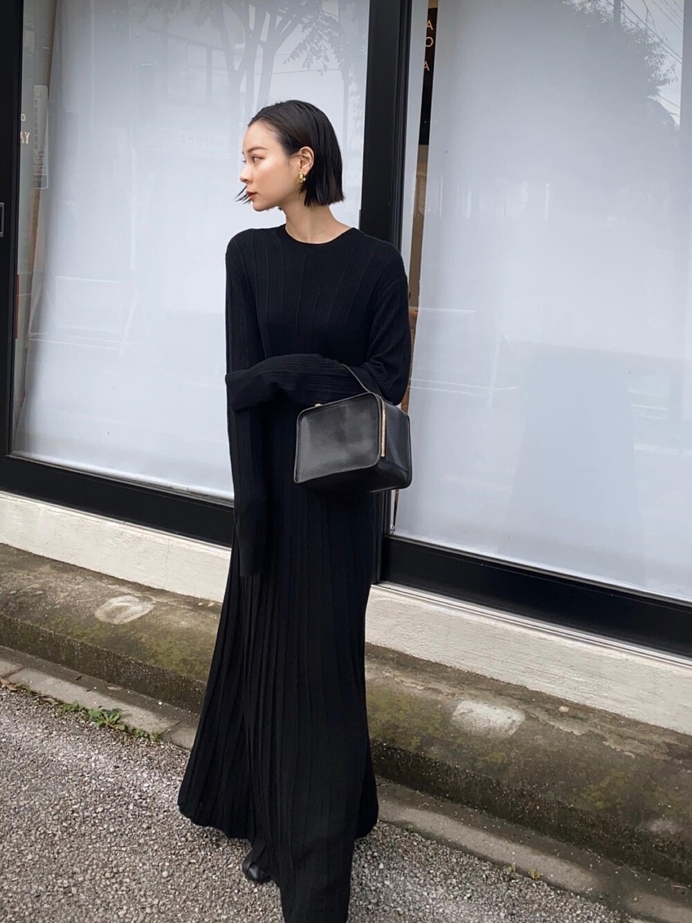ブラック系のワンピース、ブラック系のハンドバッグを着用したレディースの秋コーディネートの2枚目の写真