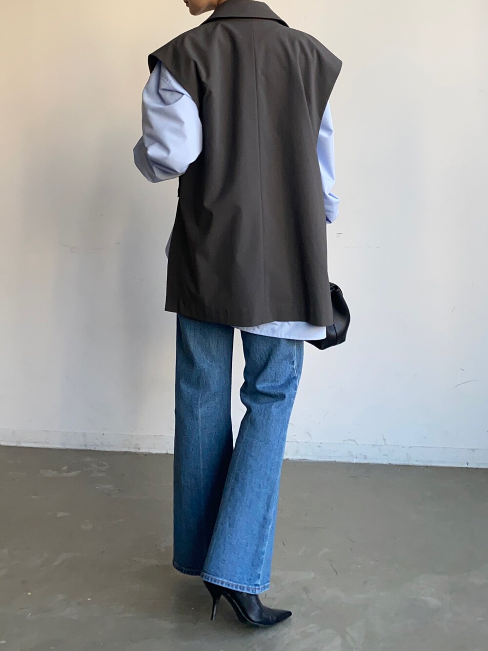 ブルー系のデニムパンツ、グレー系のベストを着用したレディースの秋コーディネートの2枚目の写真