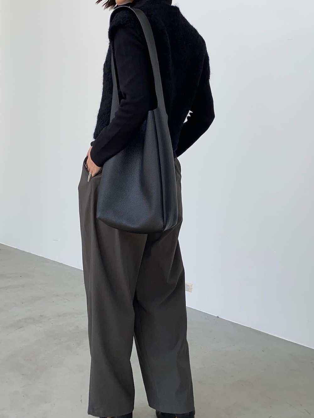 グレー系のスラックス、ブラック系のトートバッグ、ブラック系のブーツを着用したレディースの秋コーディネートの3枚目の写真