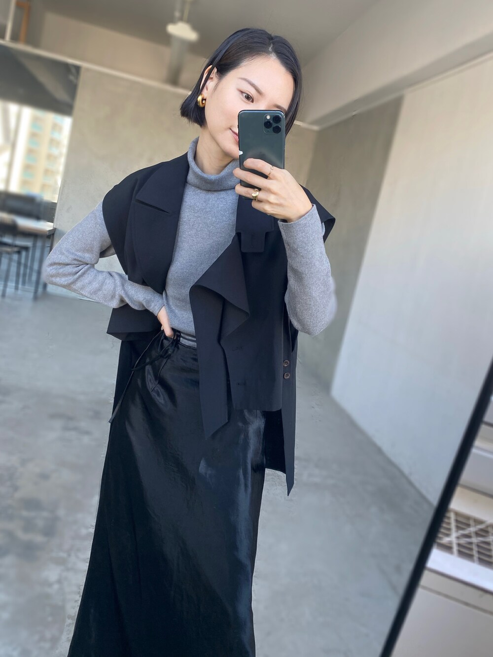 グレー系のニット/セーター、ブラック系のベスト、ブラック系のスカートを着用したレディースの秋コーディネートの2枚目の写真