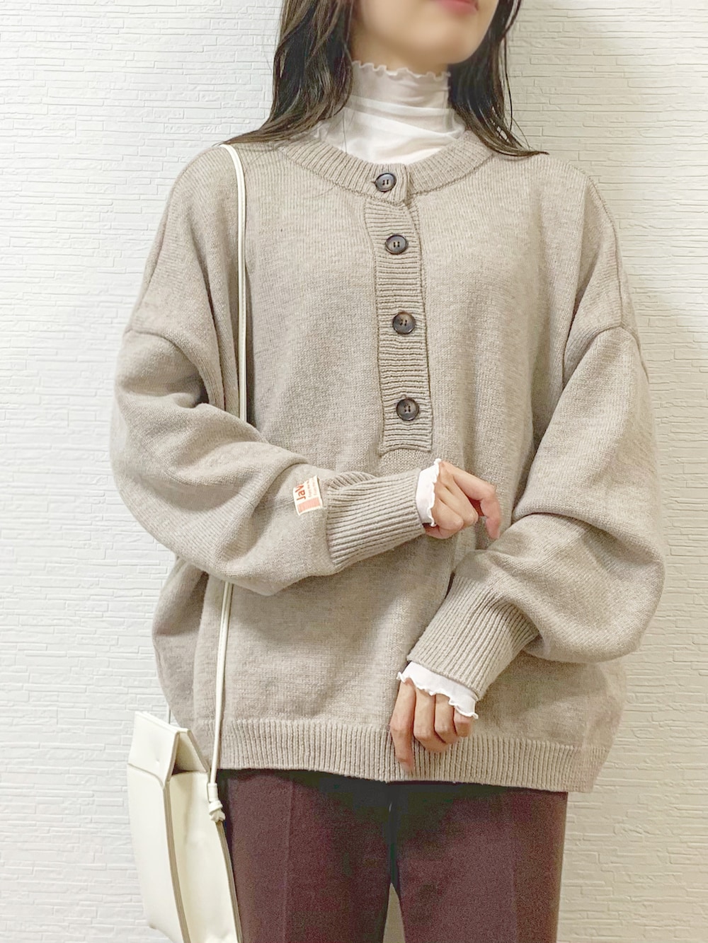 ベージュ系のニット/セーター、ホワイト系のTシャツ/カットソー、ブラウン系のスラックスを着用したレディースの冬コーディネートの2枚目の写真