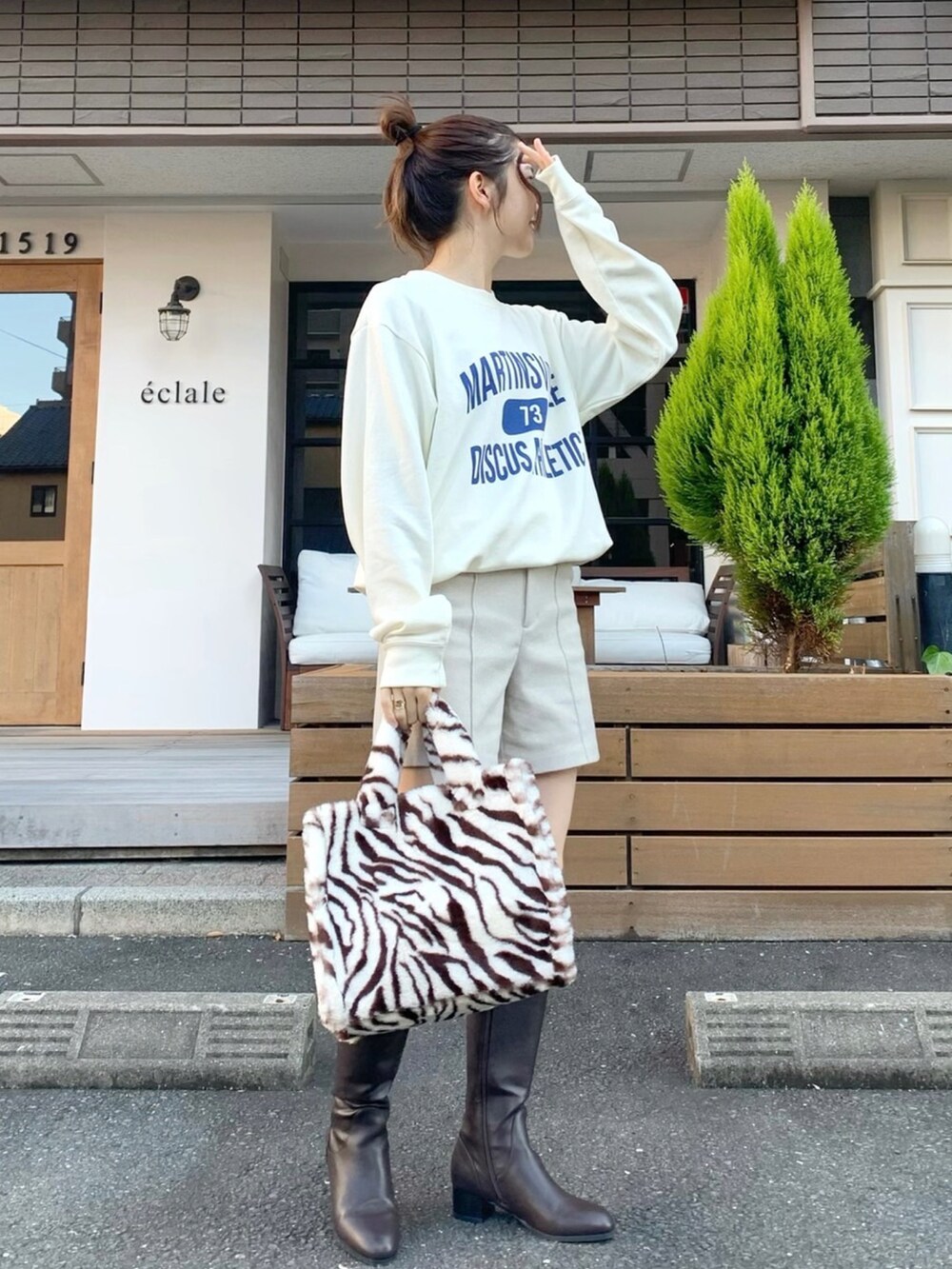 ホワイト系のスウェット、ホワイト系のパンツ、ブラウン系のバッグを着用したレディースの秋コーディネートの2枚目の写真