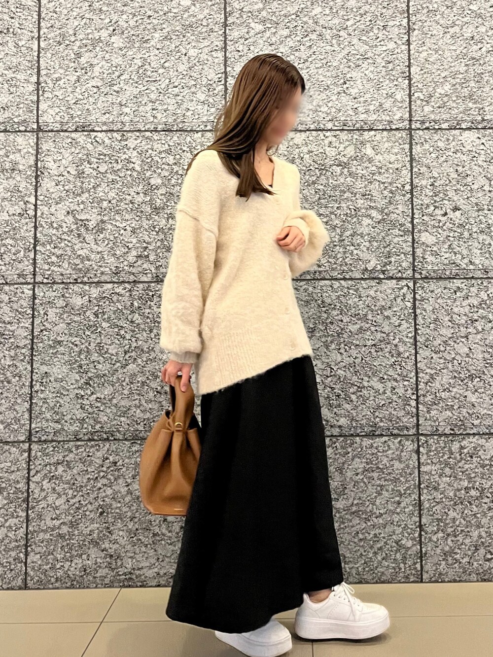 ホワイト系のカーディガン/ボレロ、ブラック系のスカート、ブラウン系のハンドバッグを着用したレディースの冬コーディネートの2枚目の写真