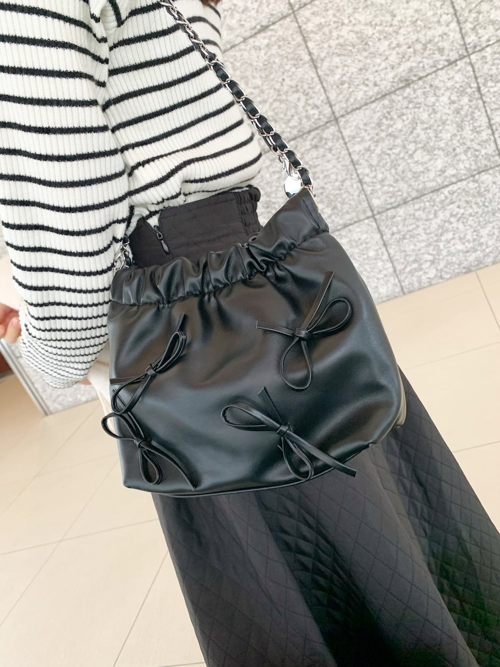 ホワイト系のニット/セーター、ブラック系のスカート、ブラック系のショルダーバッグを着用したレディースの冬コーディネートの4枚目の写真