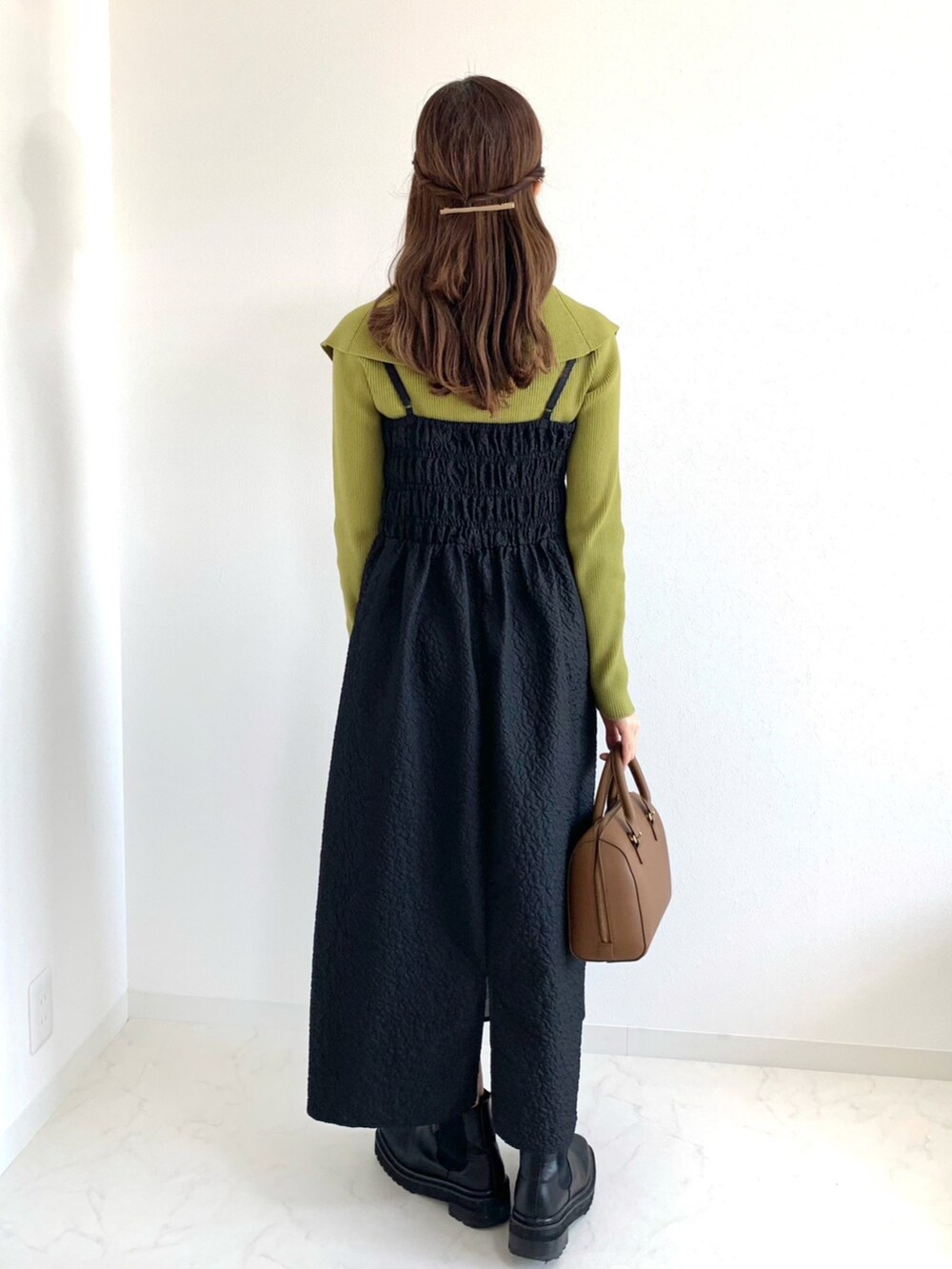 グリーン系のニット/セーター、ブラック系のワンピース、ブラウン系のボストンバッグを着用したレディースの春コーディネートの2枚目の写真