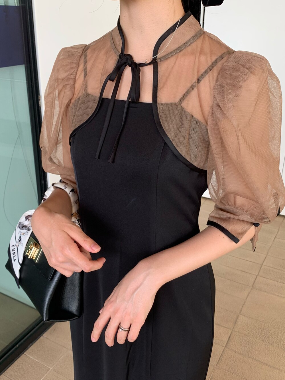 ブラック系のドレス、ブラック系のハンドバッグを着用したレディースの秋コーディネートの3枚目の写真