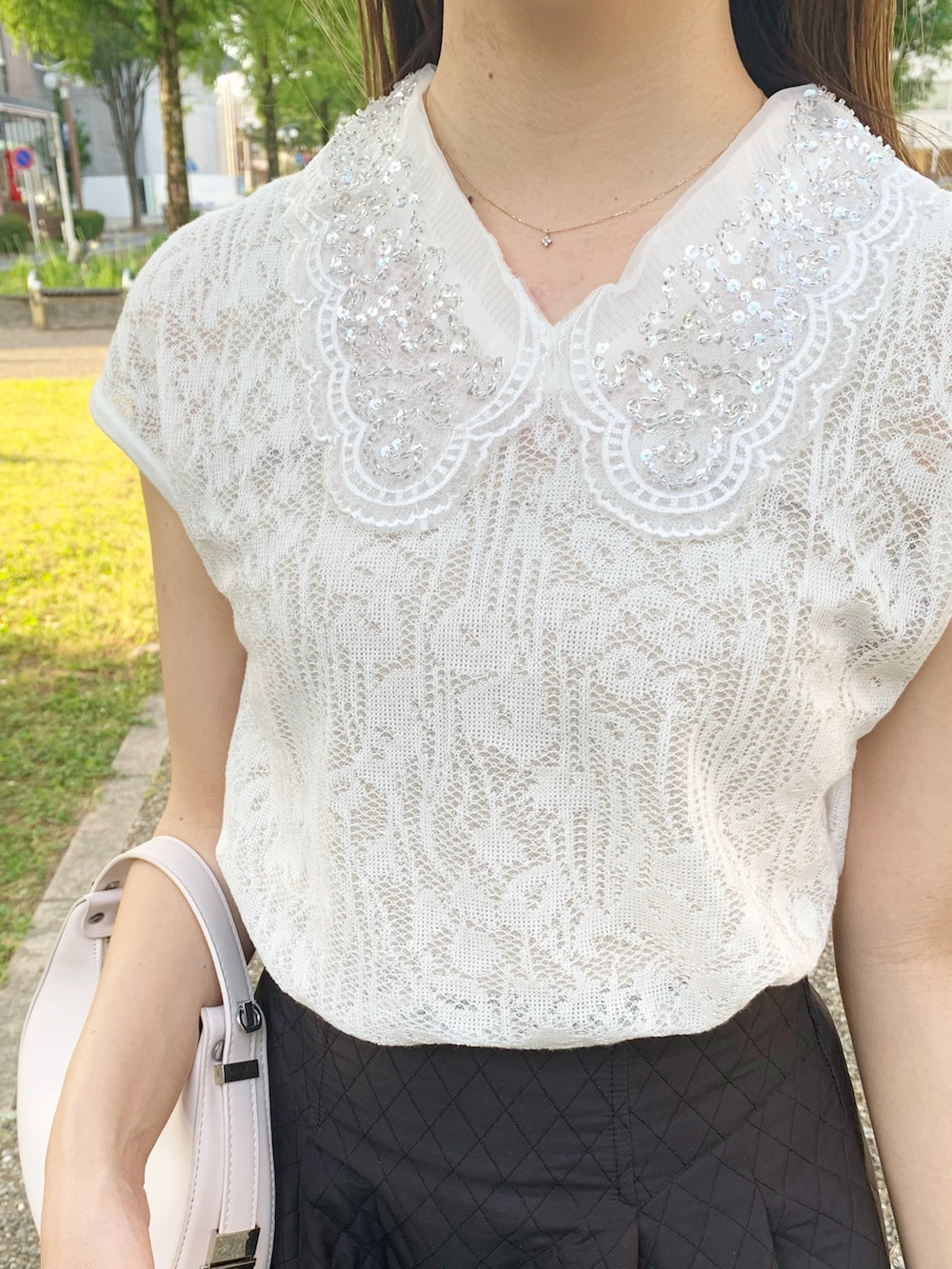 ホワイト系のTシャツ/カットソー、ホワイト系のハンドバッグ、ブラック系のスカートを着用したレディースの夏コーディネートの2枚目の写真