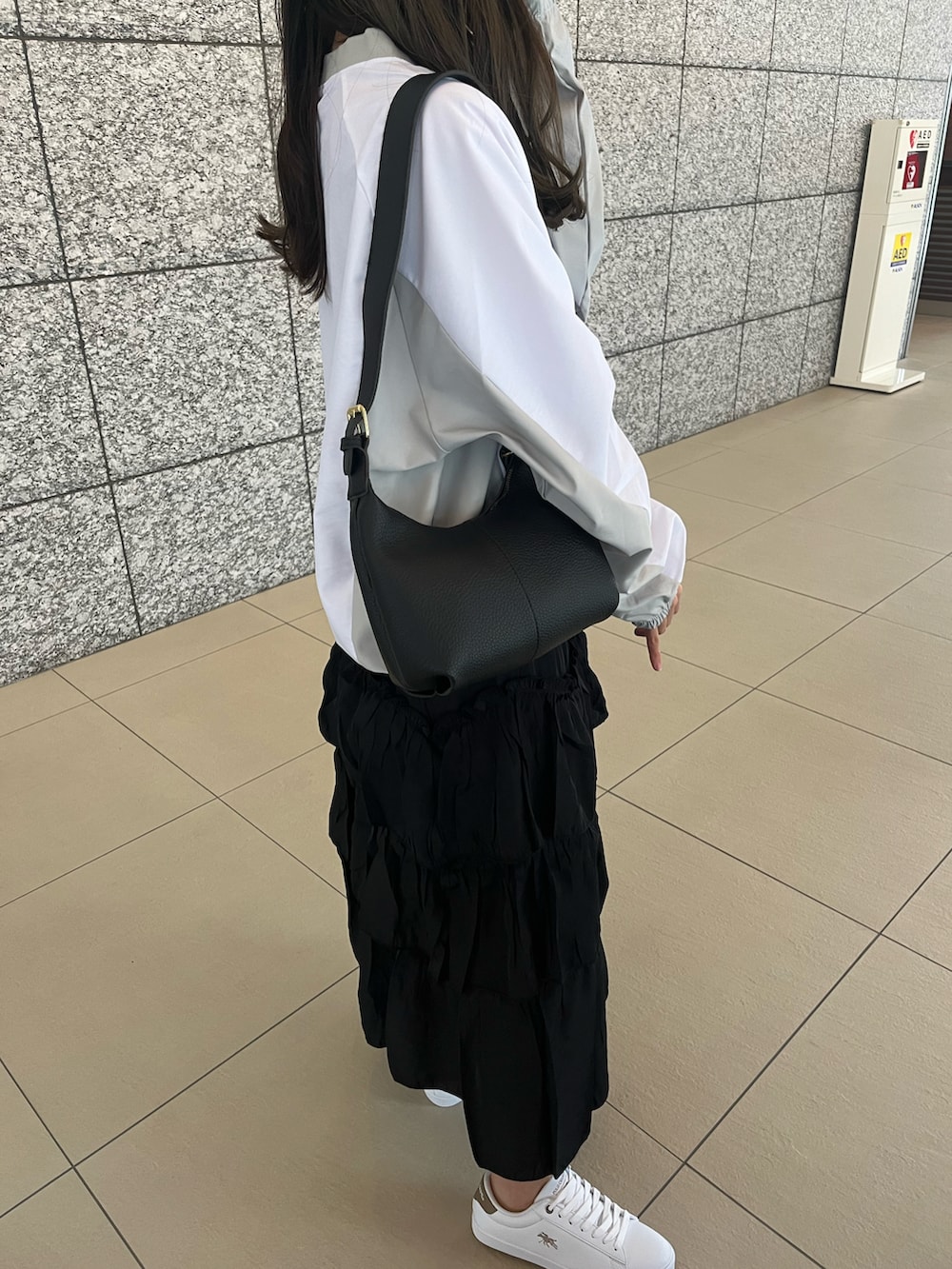 ホワイト系のTシャツ/カットソー、ブラック系のスカート、ブラック系のショルダーバッグを着用したレディースの冬コーディネートの3枚目の写真