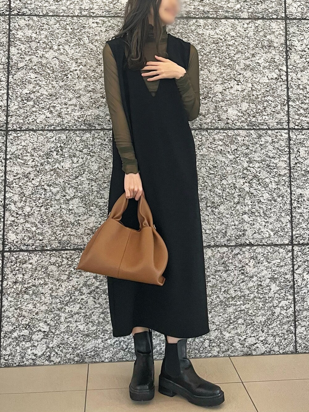 グリーン系のTシャツ/カットソー、ブラック系のジャンパースカート、ブラウン系のハンドバッグを着用したレディースの春コーディネートの2枚目の写真