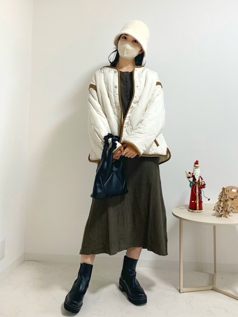 ホワイト系のブルゾン、ブラウン系のワンピース、ブラック系のバッグを着用したレディースの冬コーディネートの2枚目の写真