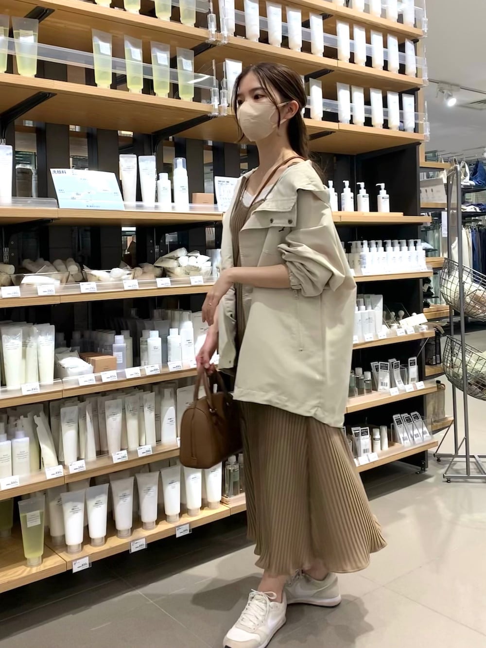 ホワイト系のマウンテンパーカー、ベージュ系のワンピース、ベージュ系のスニーカーを着用したレディースの春コーディネートの2枚目の写真