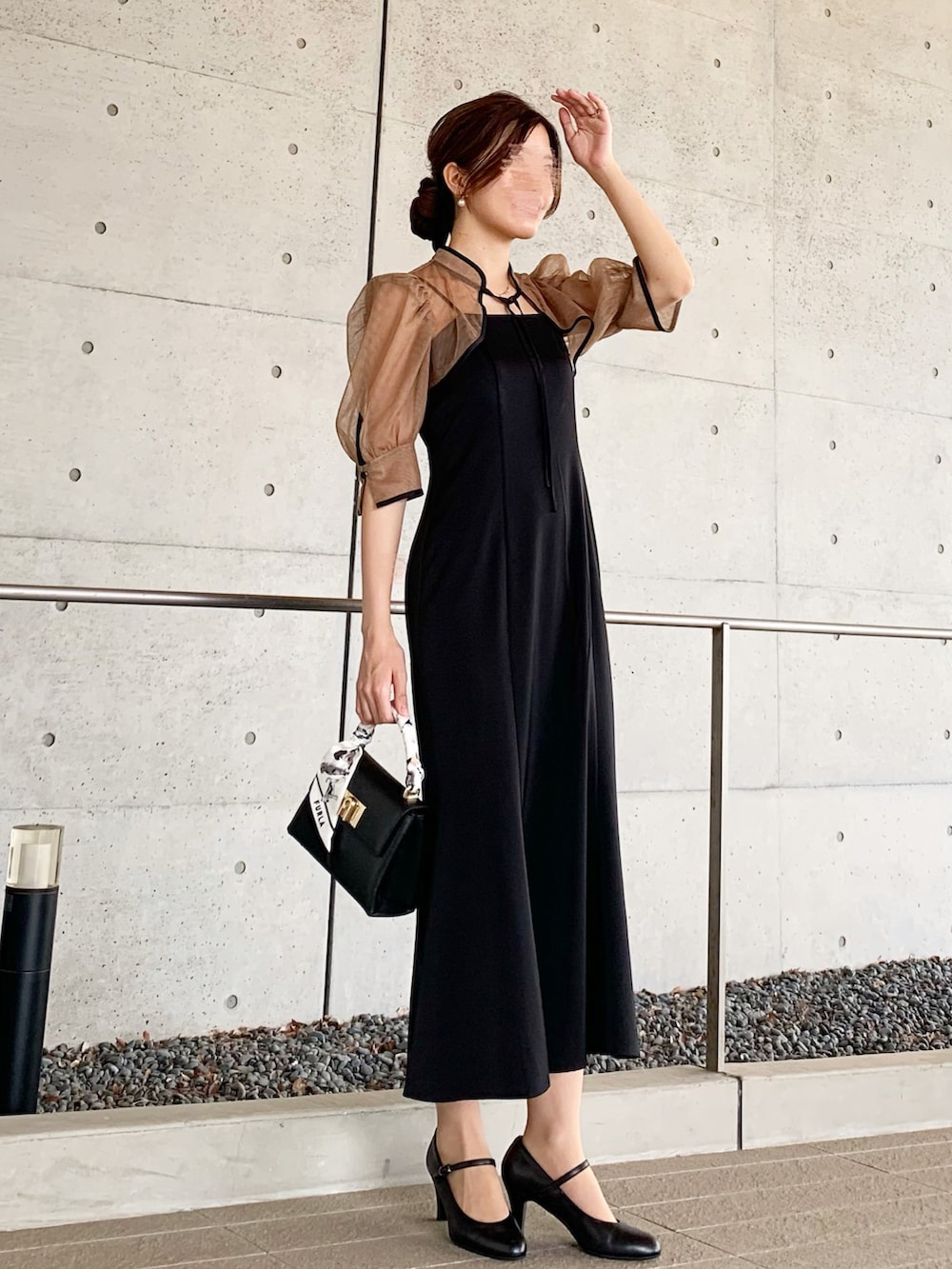 ブラック系のドレス、ブラック系のハンドバッグを着用したレディースの秋コーディネートの2枚目の写真